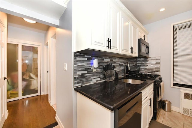 kitchen with sink, white cabinetry, radiator, decorative backsplash, and black appliances