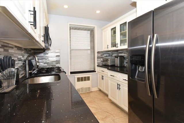 kitchen featuring radiator heating unit, sink, dark stone countertops, white cabinets, and stainless steel refrigerator with ice dispenser