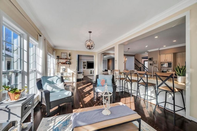 dining room featuring wood-type flooring, ornamental molding, sink, and an inviting chandelier