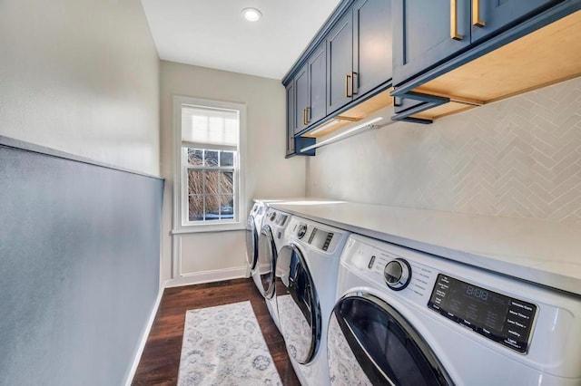 clothes washing area featuring cabinets, dark hardwood / wood-style floors, and washer and clothes dryer