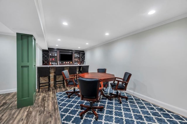 dining room featuring dark hardwood / wood-style flooring, crown molding, and bar area