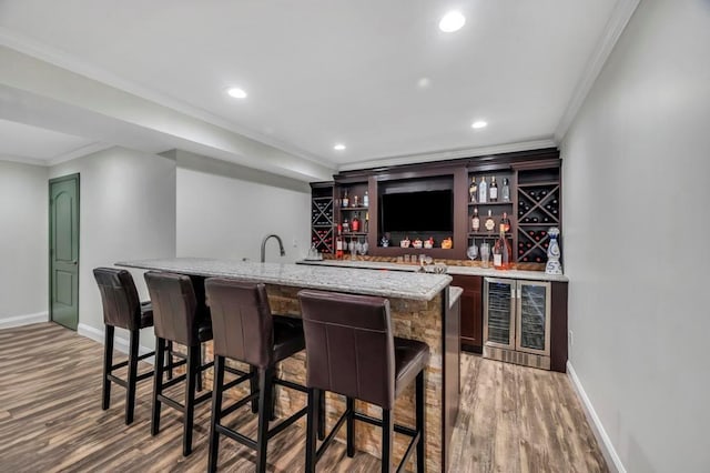 bar featuring wine cooler, sink, crown molding, light stone counters, and hardwood / wood-style floors