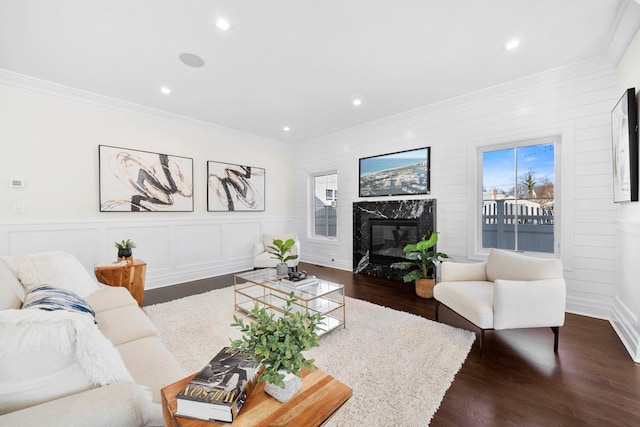 living room with a premium fireplace, crown molding, and dark wood-type flooring