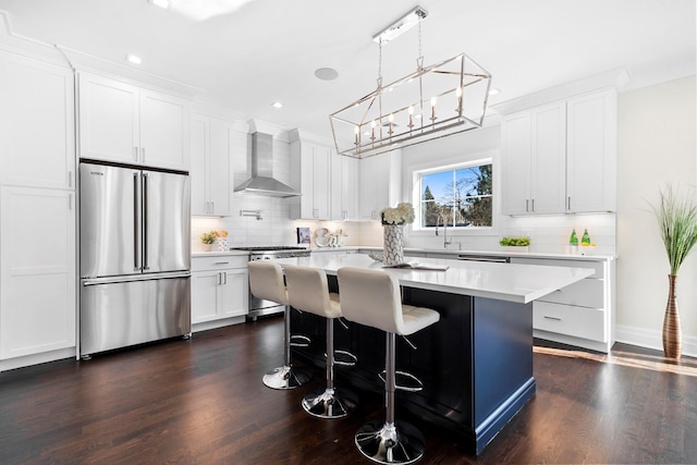 kitchen featuring white cabinets, high quality fridge, wall chimney exhaust hood, and range