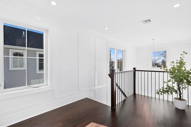 corridor with ornamental molding, plenty of natural light, and dark wood-type flooring