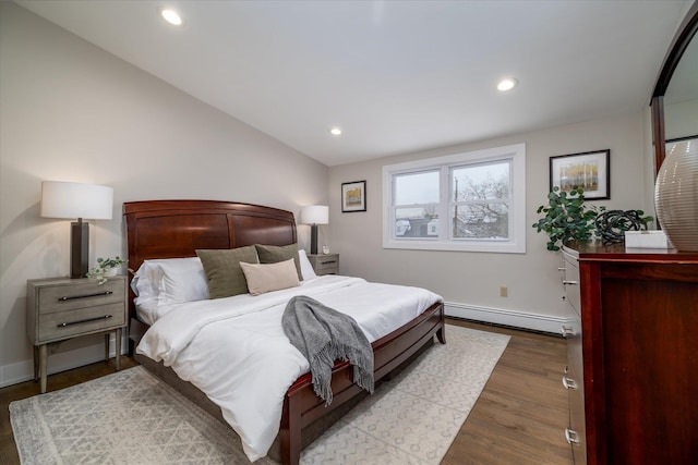 bedroom with baseboard heating, hardwood / wood-style floors, and lofted ceiling