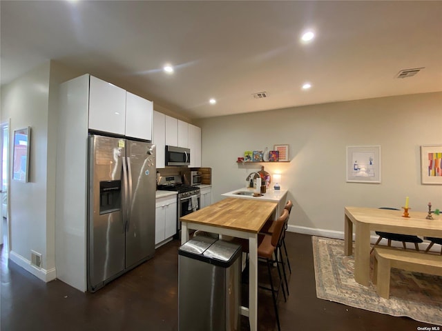 kitchen featuring white cabinets, stainless steel appliances, sink, kitchen peninsula, and a breakfast bar