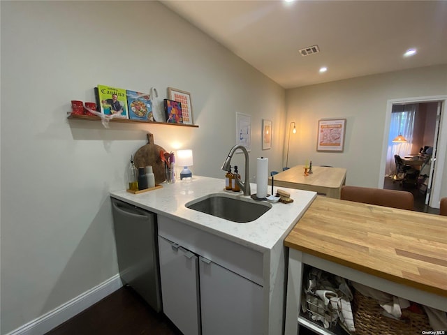 kitchen with sink, stainless steel dishwasher, and light stone counters