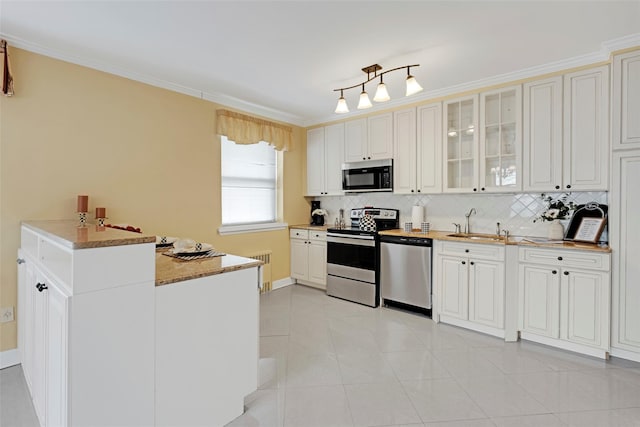 kitchen with appliances with stainless steel finishes, sink, white cabinets, ornamental molding, and light tile patterned floors