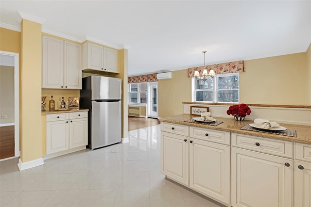 kitchen with decorative light fixtures, stainless steel fridge, light tile patterned floors, light stone counters, and cream cabinets