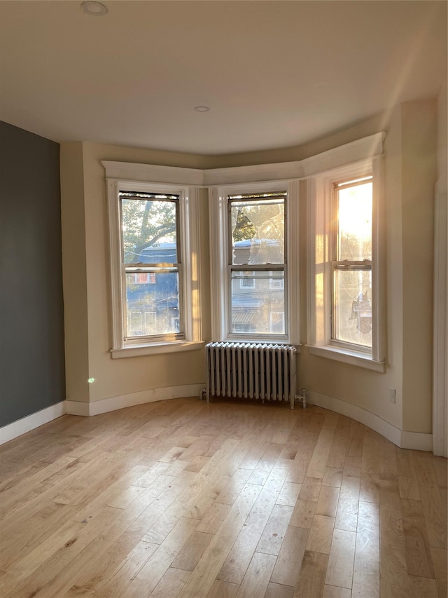 unfurnished room with light wood-type flooring and radiator heating unit