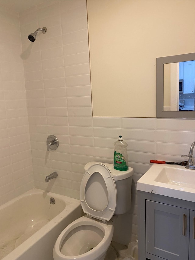 full bathroom featuring vanity, toilet, tile walls, and tiled shower / bath combo