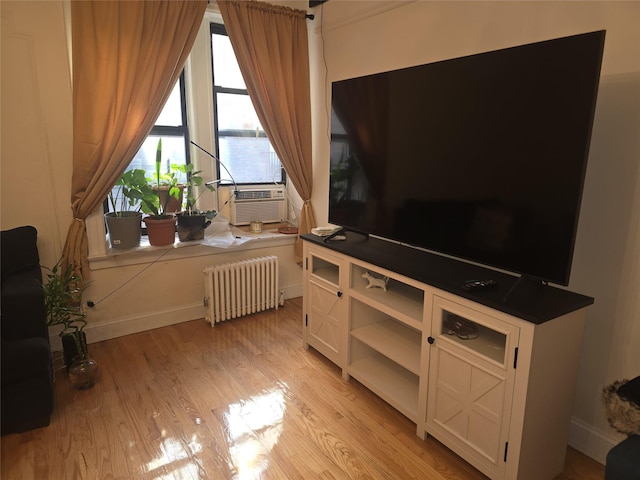 living room with cooling unit, radiator heating unit, and light wood-type flooring