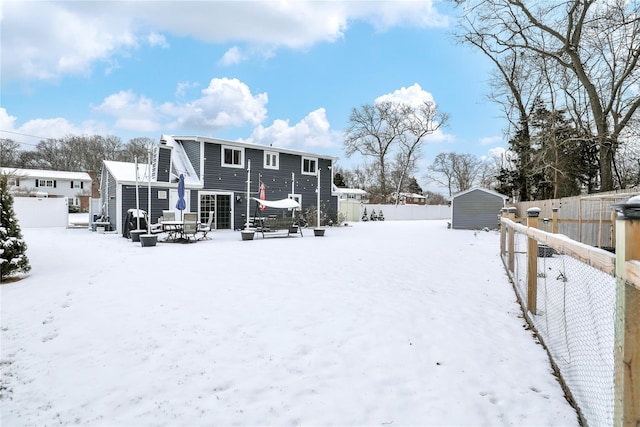 snow covered house featuring a shed