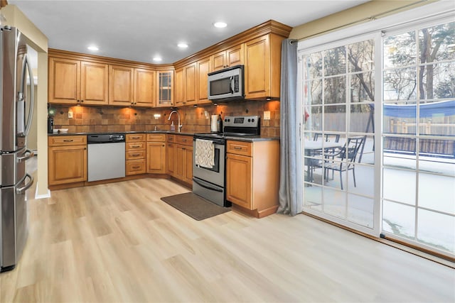 kitchen with decorative backsplash, sink, appliances with stainless steel finishes, and light hardwood / wood-style flooring