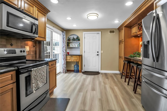 kitchen featuring backsplash, light hardwood / wood-style floors, and stainless steel appliances