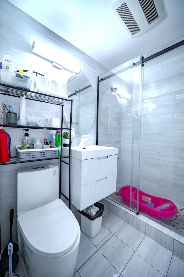 bathroom featuring tile patterned floors, toilet, an enclosed shower, tile walls, and vanity