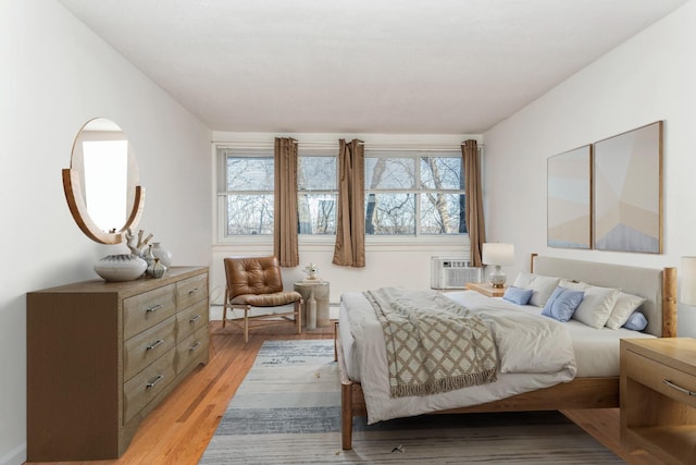 bedroom featuring a wall unit AC and light hardwood / wood-style flooring