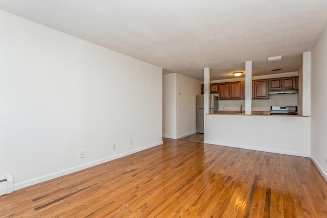 unfurnished living room with light hardwood / wood-style flooring and a baseboard heating unit