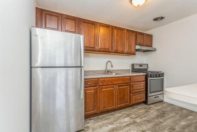 kitchen featuring stainless steel appliances, sink, and light hardwood / wood-style flooring