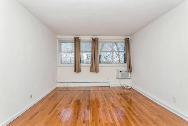 empty room featuring baseboard heating, light hardwood / wood-style floors, and an AC wall unit