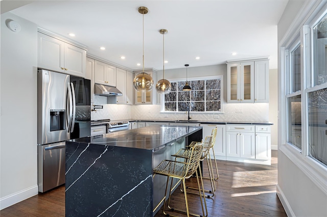 kitchen with decorative light fixtures, tasteful backsplash, white cabinetry, a kitchen island, and stainless steel appliances