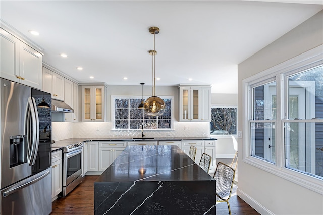 kitchen featuring tasteful backsplash, hanging light fixtures, stainless steel appliances, and a kitchen island