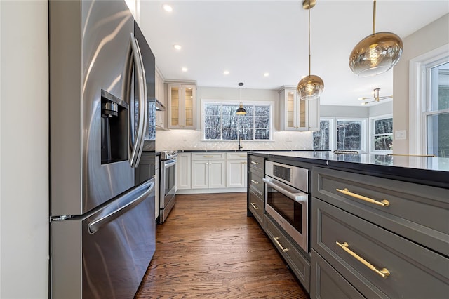 kitchen featuring white cabinets, decorative light fixtures, dark hardwood / wood-style flooring, stainless steel appliances, and backsplash