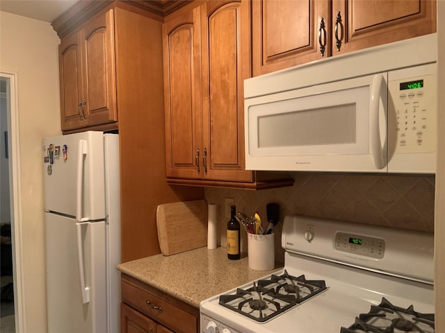 kitchen featuring backsplash, white appliances, and light stone countertops