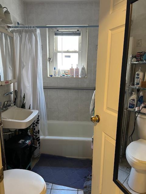 full bathroom featuring sink, tile patterned floors, shower / bath combo with shower curtain, and toilet