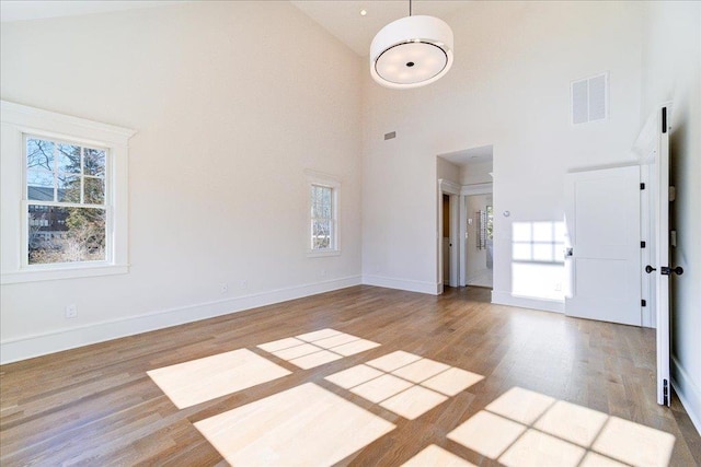 unfurnished living room featuring wood finished floors, visible vents, and a healthy amount of sunlight