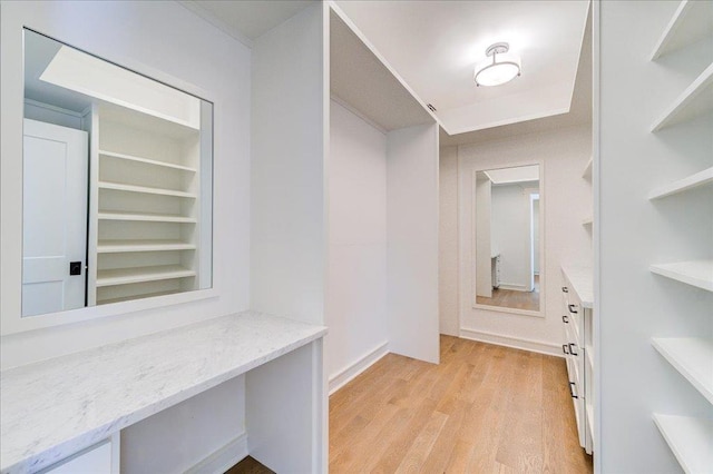 walk in closet featuring light wood finished floors and built in study area