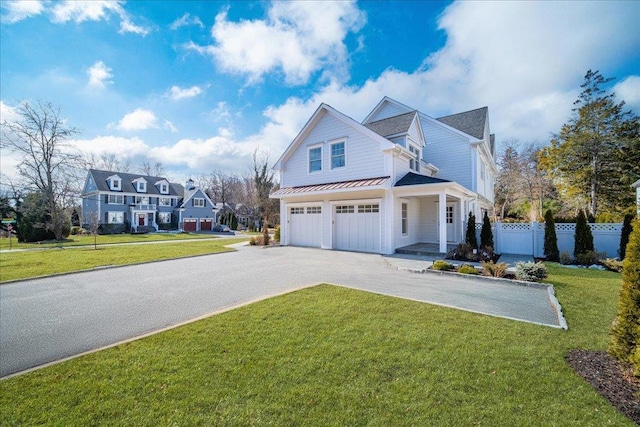 view of front of home featuring a standing seam roof, fence, metal roof, a garage, and driveway