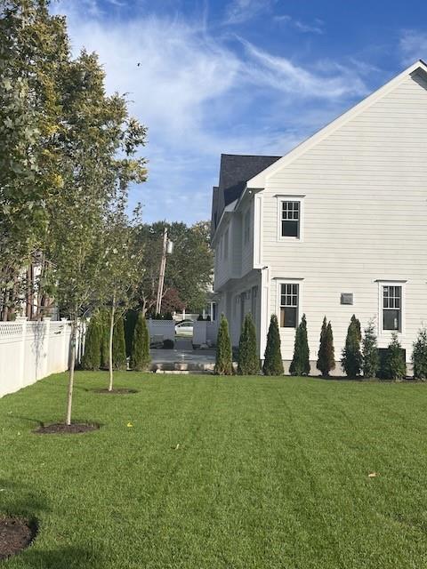 view of home's exterior with a lawn and fence