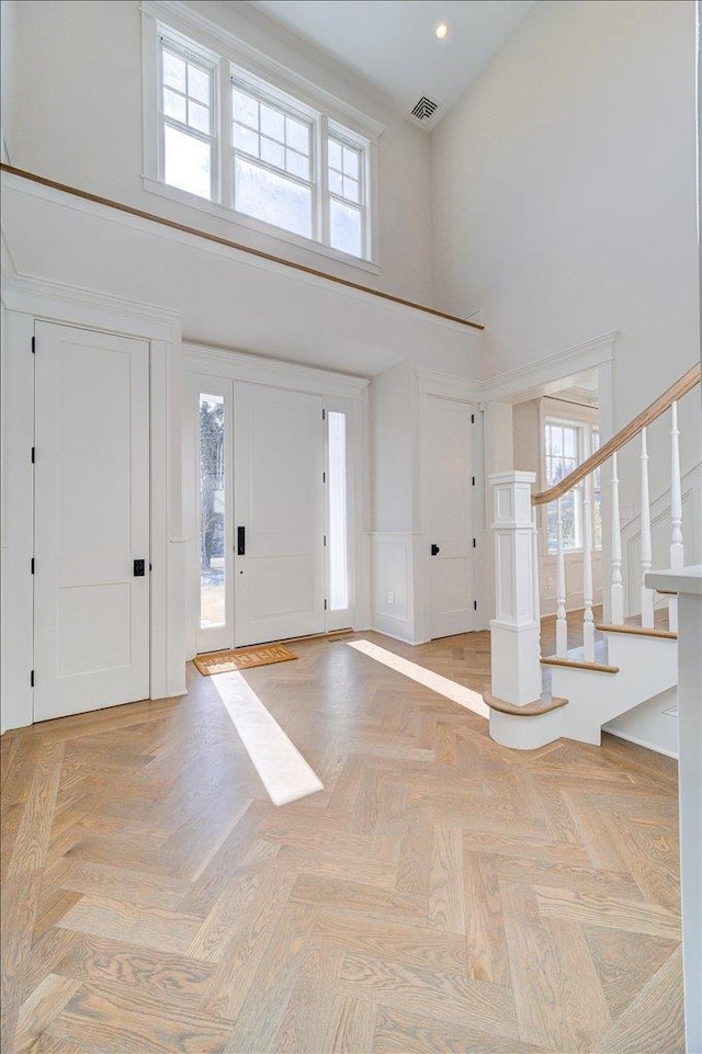 entrance foyer with a high ceiling, stairway, and visible vents