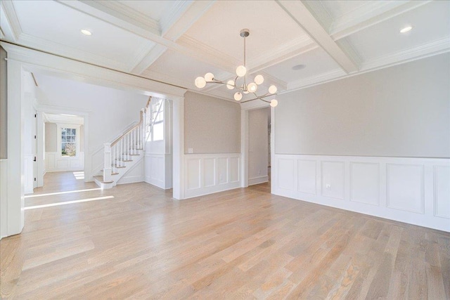 spare room with light wood-type flooring, beam ceiling, coffered ceiling, and stairway