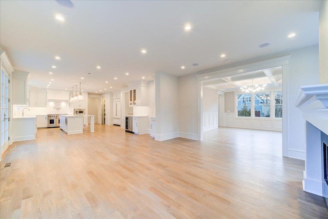 unfurnished living room featuring a chandelier, light wood-type flooring, a fireplace, and recessed lighting