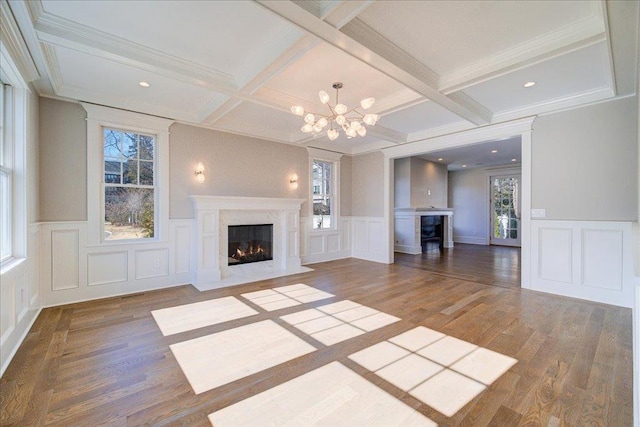 unfurnished living room featuring beamed ceiling, a fireplace, wood finished floors, and a wealth of natural light