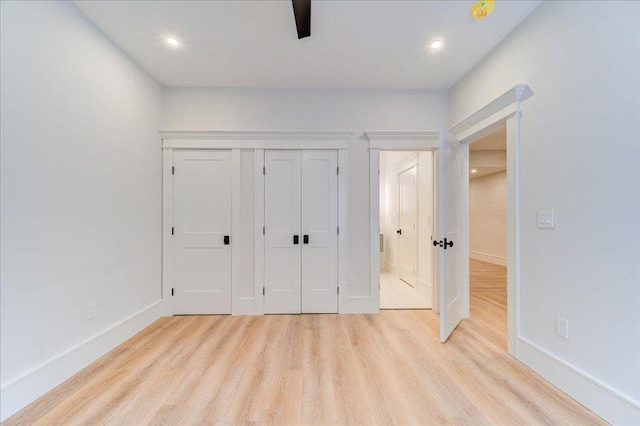 unfurnished bedroom featuring a closet, recessed lighting, wood finished floors, and baseboards