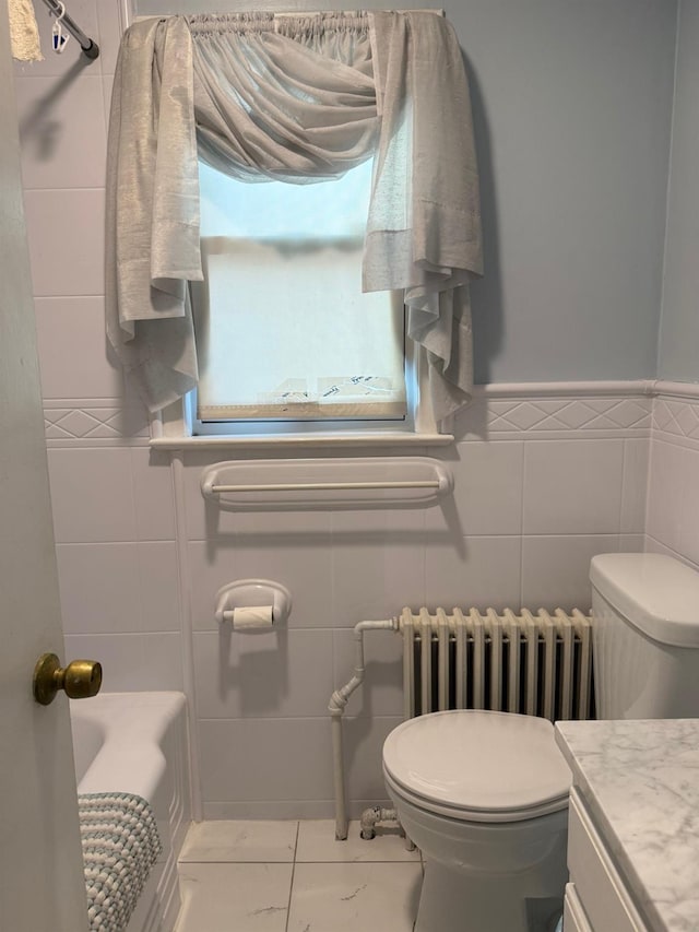 bathroom featuring tile walls, radiator, vanity, and toilet