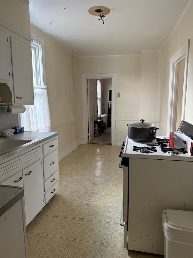 kitchen with white cabinetry, white gas range, and sink