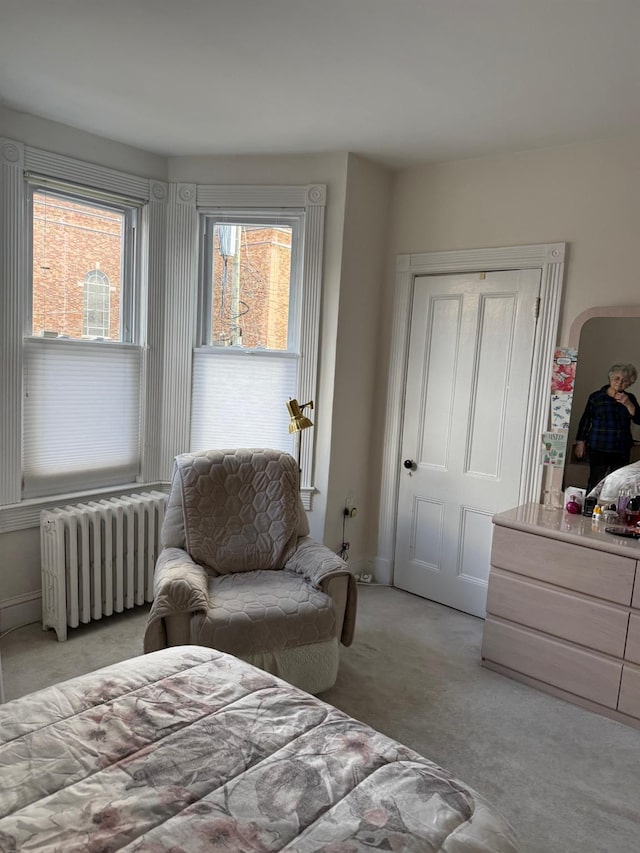 bedroom featuring radiator heating unit and light carpet