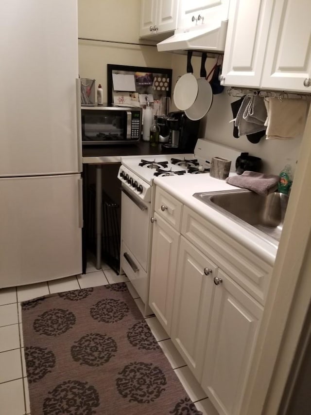 kitchen with sink, light tile patterned flooring, white appliances, and white cabinetry