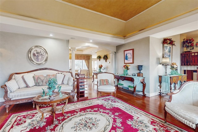 living room featuring hardwood / wood-style flooring, ornamental molding, a raised ceiling, and ornate columns