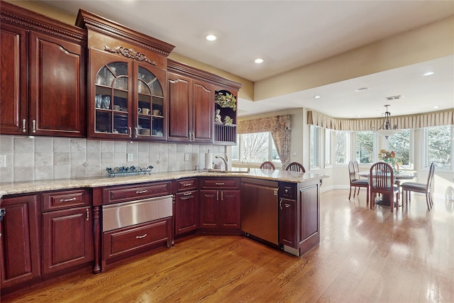 kitchen featuring sink, hardwood / wood-style flooring, dishwasher, pendant lighting, and decorative backsplash