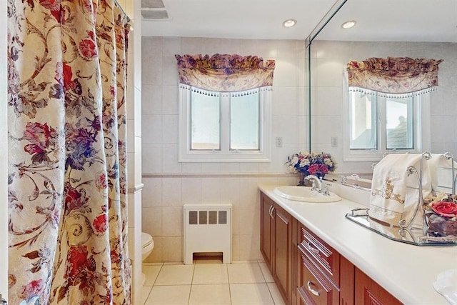 bathroom with radiator heating unit, tile walls, vanity, toilet, and tile patterned floors