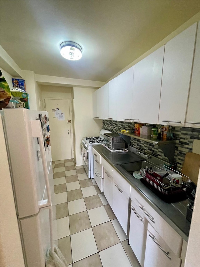 kitchen with white cabinetry, white appliances, dark countertops, and backsplash