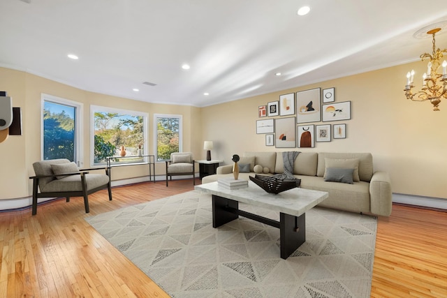 living room with wood-type flooring, crown molding, and a notable chandelier