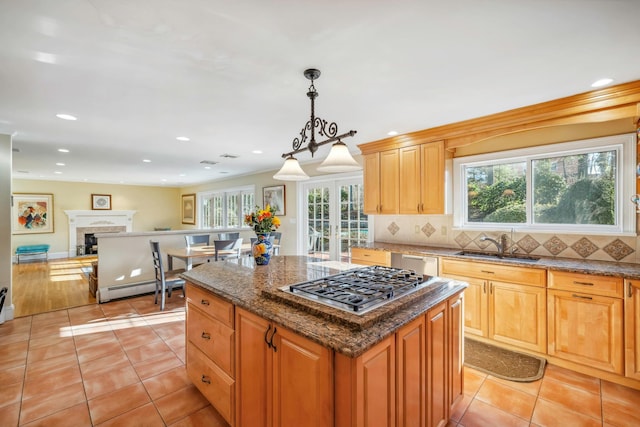 kitchen featuring pendant lighting, appliances with stainless steel finishes, a kitchen island, sink, and light tile patterned floors