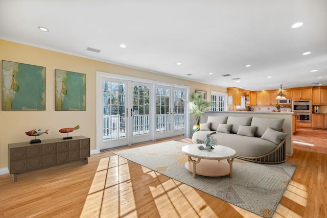 living room with light hardwood / wood-style floors, crown molding, and french doors